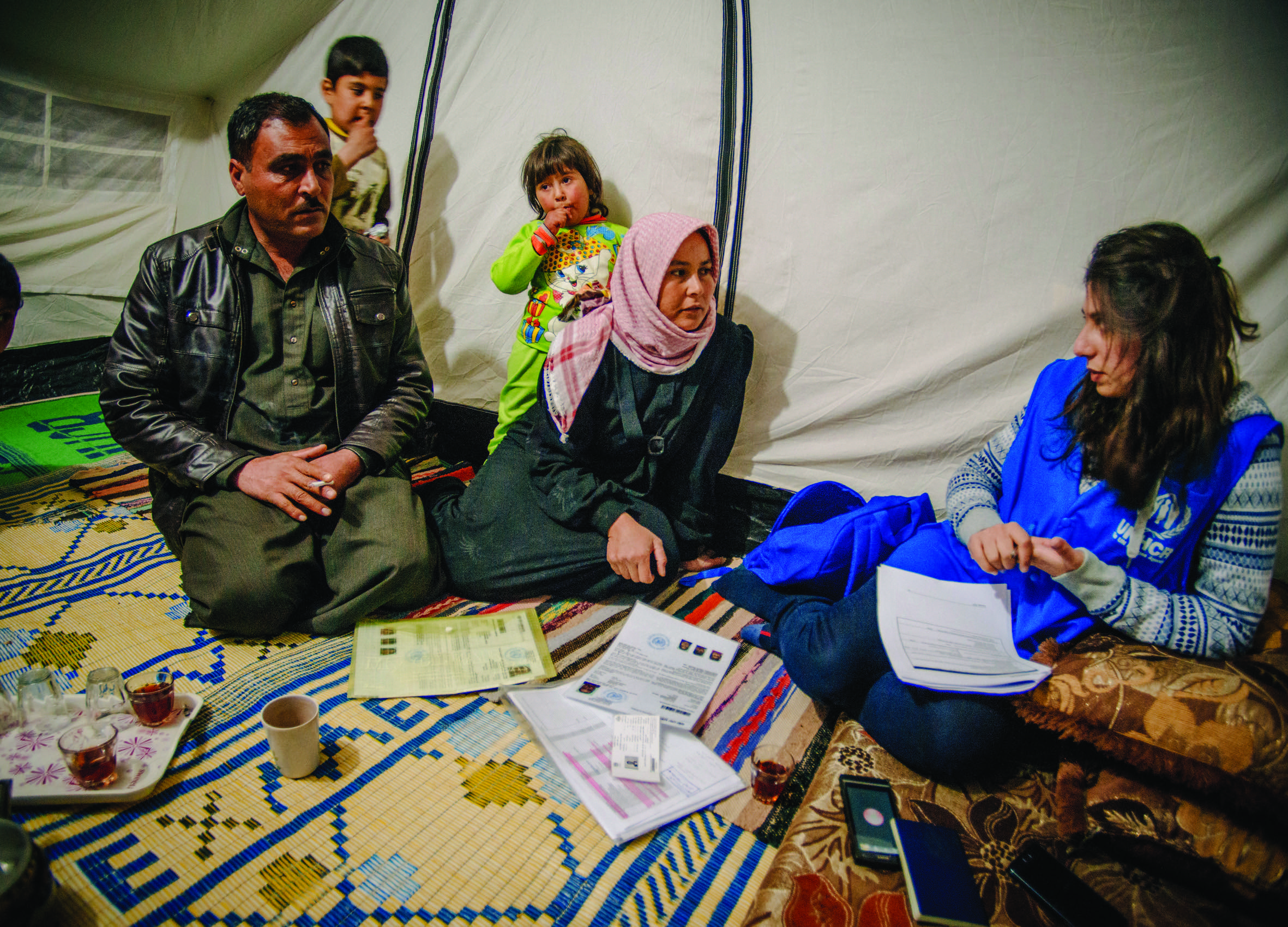 A Syrian refugee family tells a UNHCR staff member about life in a tented settlement.