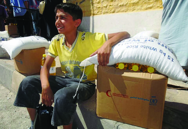 A Syrian boy collects his family’s monthly ration of rice, flour, pasta, beans, vegetable oil, sugar and yeast.