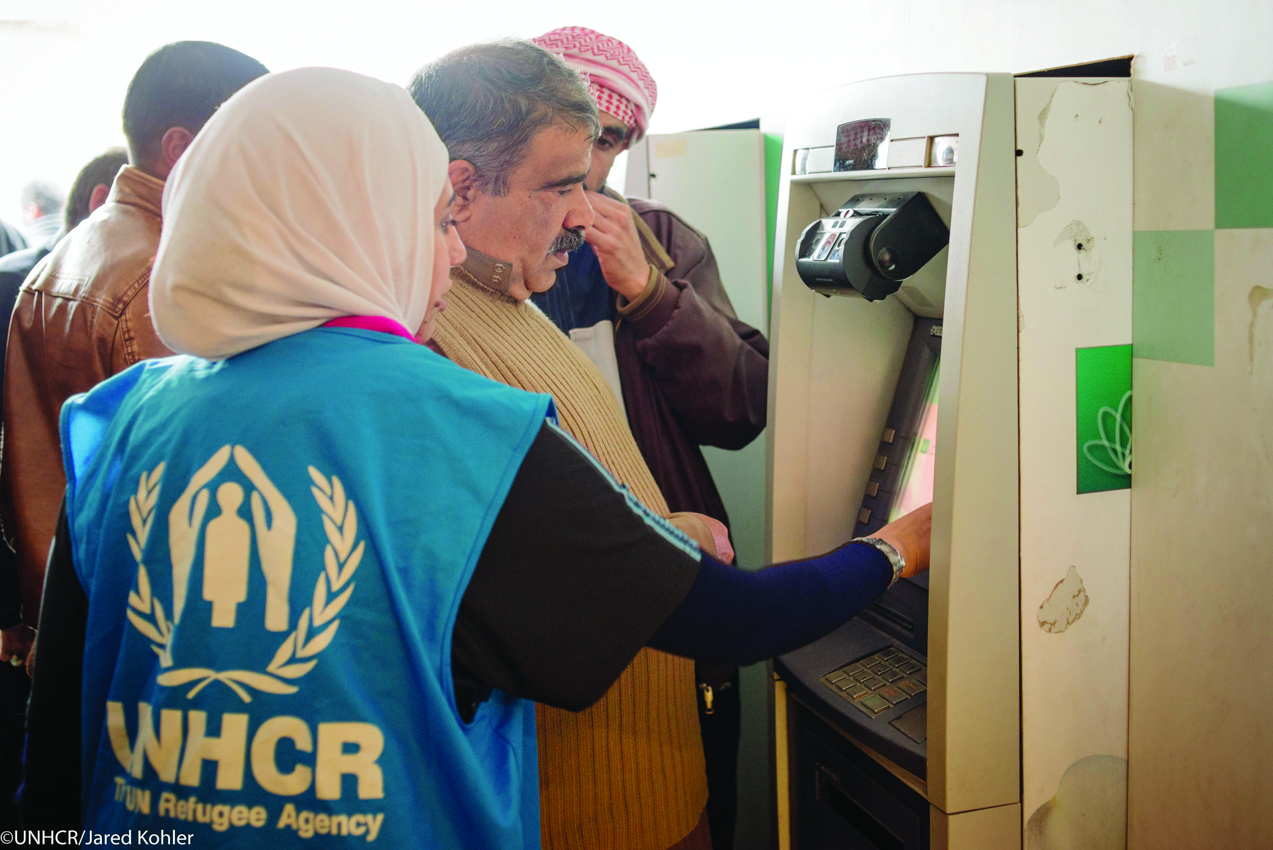 UNHCR staff assisting Syrian refugee with their first-time access to cash assistance through iris scanning, Mafraq, Jordan.