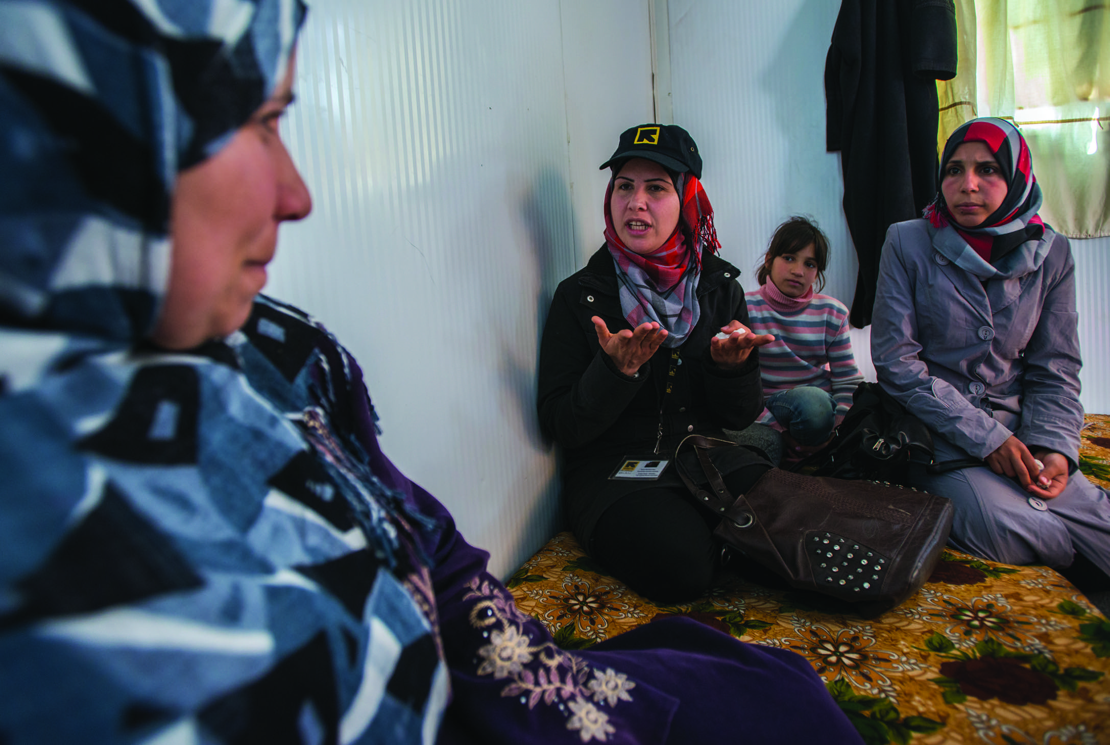 IRC volunteer Rania speaks with a Syrian refugee at a refugee camp in Jordan. Rania is a Syrian refugee who meets with as many as 50 families per week to inform them about available programming and support in the camp.