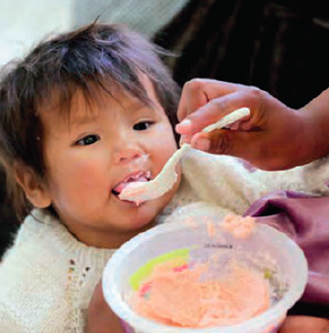 A mother feeds her child fortified porridge in Bolivia