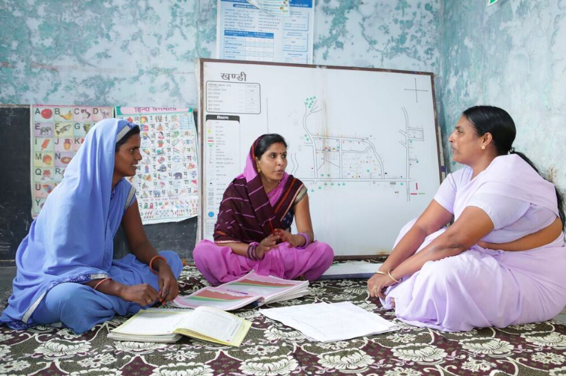 Réunion des trois travailleuses communautaires en santé et nutrition au village de Khandi, à Rajasthan avec une carte du village 