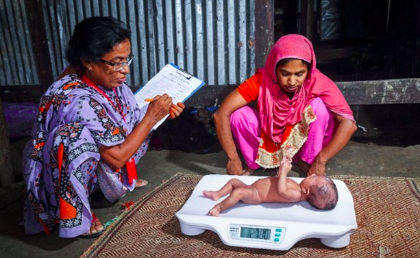 Field research officers measure the weight of an infant under six months in Barisal, Bangladesh, 2016