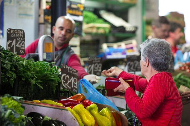 Un client achète des légumes frais sur un stand de légumes dans un marché urbain en Italie