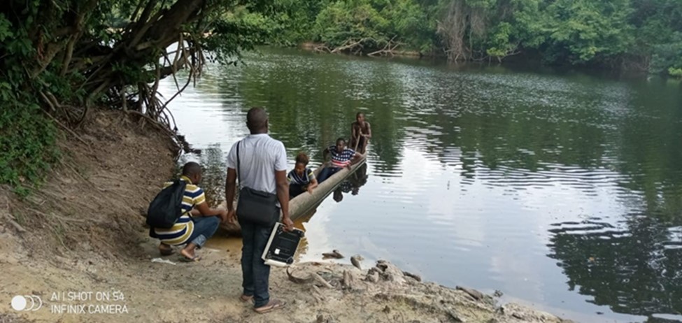Survey teams crossing a river to access a remote area for data collection in Liberia, 2020