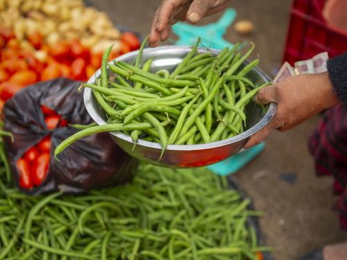 A bowl of green beans being weighed and bought in a local market