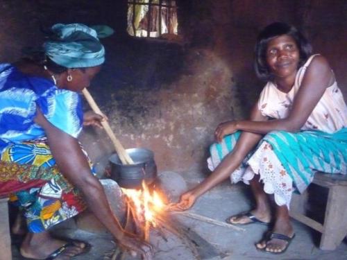 Two women cooking on a fire inside their home