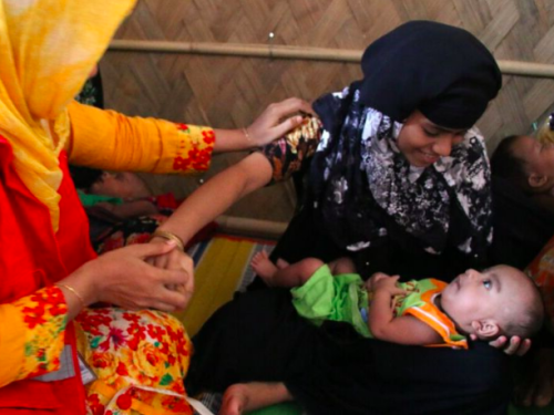 FB MAMI counsellor measures the MUAC of a mother whilst she holds her baby at a C-MAMI site, Cox's Bazar, Bangladesh