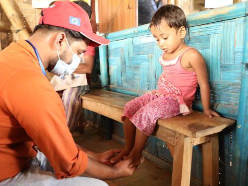Development aid worker measuring a little girl's feet