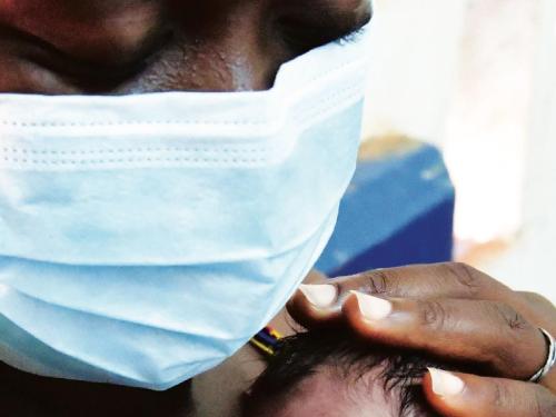 Photo of a woman wearing a mask while hugging her newborn baby