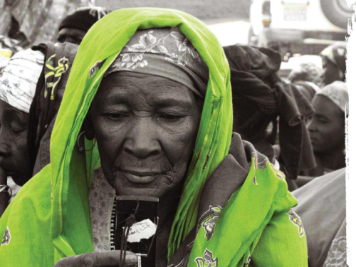 Picture shows a woman in black and white apart from her head scarf which is green.