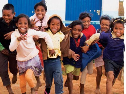 Image shows a group of children running happily towards the camera.