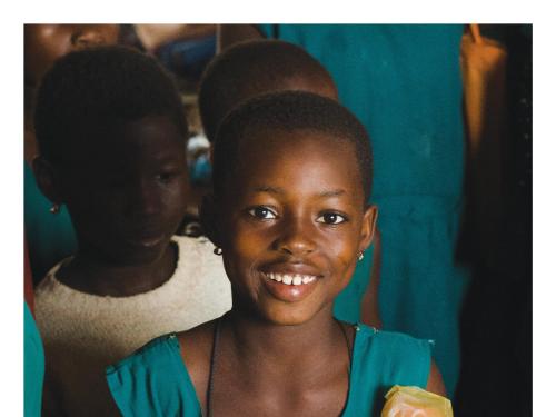 Front cover of report titled, "Story of change: Wasting and stunting project." Image shows a child smiling with peers in the background.