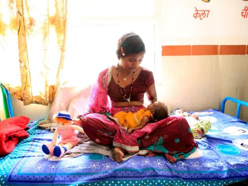 a mother and her baby on a bed, India