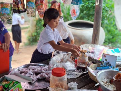 Schoolgirl taking snacks from a shop in Cambodia.