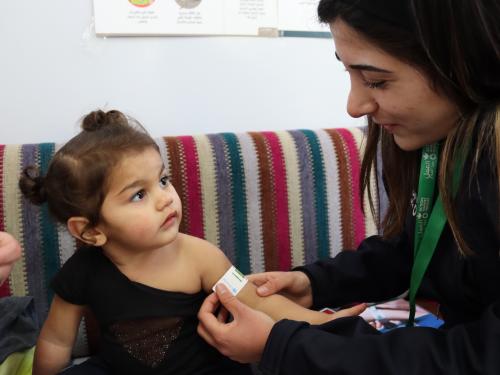 A team member from Action Against Hunger measures mid-upper arm circumference of a young girl to determine nutrition status. Lebanon, 2024