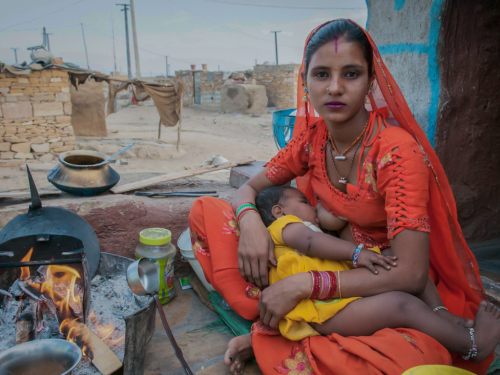 Woman breastfeeding while cooking in Rajasthan, India