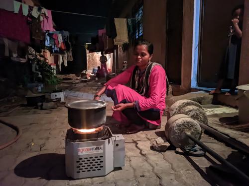 A woman in her home using a pellet based improved cookstove