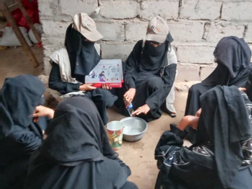 A group of women sat on the ground looking at cards. Credit Crisis Response FHI 360 Yemen