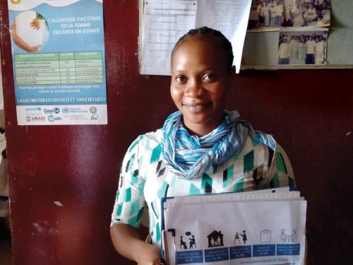 Woman standing holding paper work.