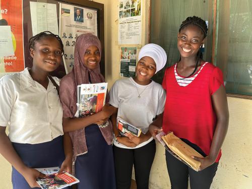 Four teenage girls stand outside a building holding their photobooks.