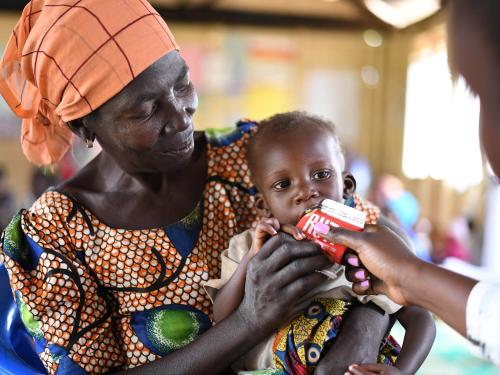 Woman holding child who is eating RUFT.