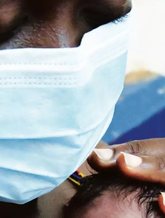 Photo of a woman wearing a mask while hugging her newborn baby