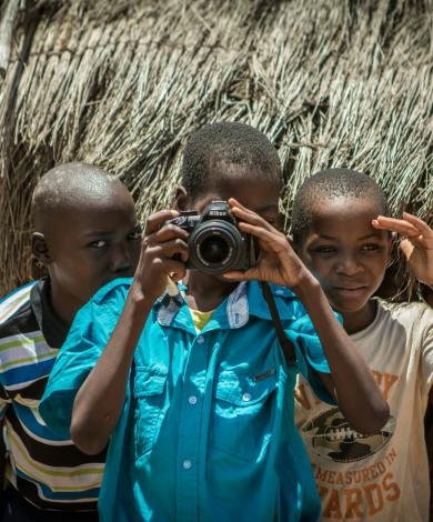 Three boys take a photo in village, Mozambique 