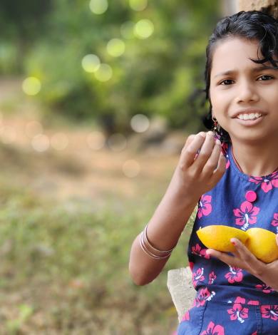 Indian girl eating an orange