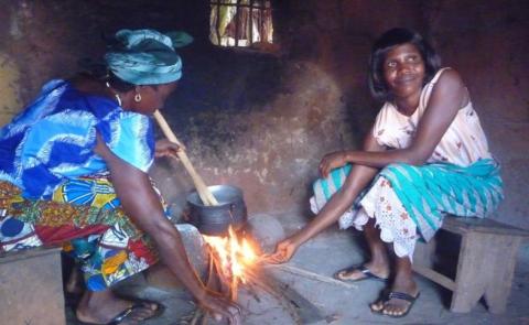 Two women cooking on a fire inside their home