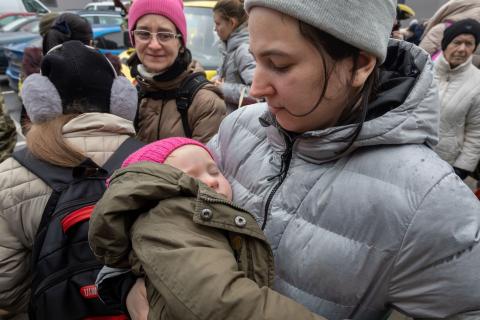 woman holding her child outside in refugee camp