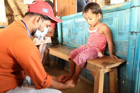 A medical professional checking a child's feet for nutritional oedema