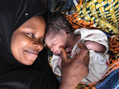 Image shows a mother cradling her new born baby. 