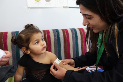 A team member from Action Against Hunger measures mid-upper arm circumference of a young girl to determine nutrition status. Lebanon, 2024