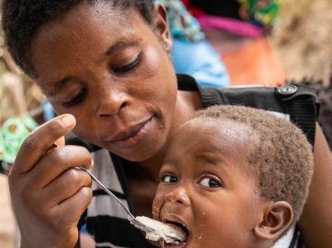 Front cover image from the Global Resilience Report. A woman spoon feeds a child.