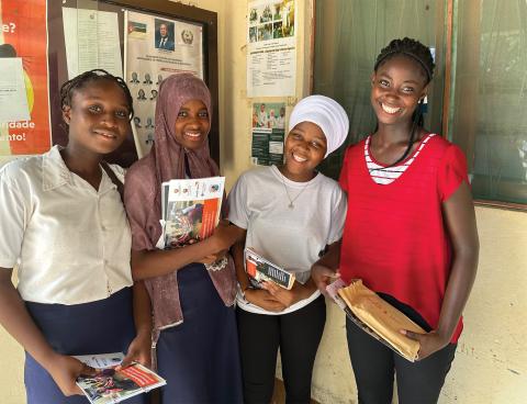 Four teenage girls stand outside a building holding their photobooks.