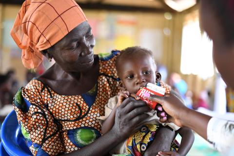 Woman holding child who is eating RUFT.