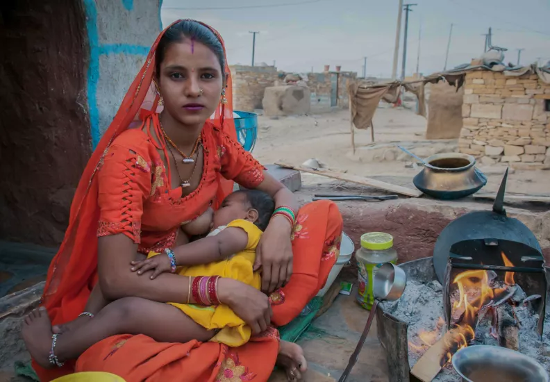 Woman breastfeeding while cooking in Rajasthan, India